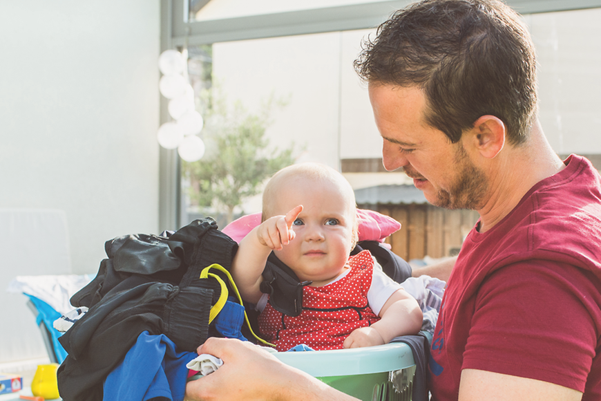 Ein Mann hält ein Baby in einem Wäschekorb in den Händen.