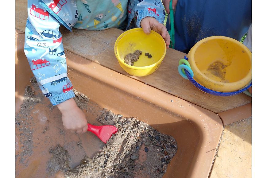 Ein Kind spielt mit einer Schaufel im Sand
