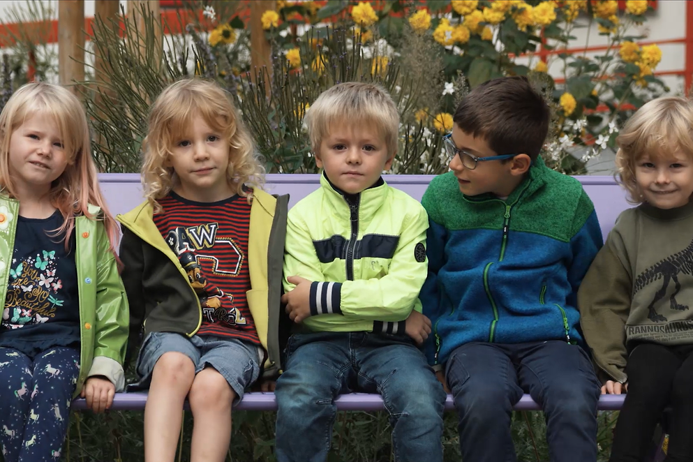 Eine Gruppe Kinder sitzt auf einer Bank.