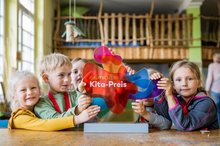 Eine Gruppe Kinder mit einer Trophäe des Deutschen Kita-Preis